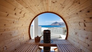 Een houten interieur met een rond raam dat uitkijkt op een balkon en de zee.