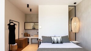 Een moderne slaapkamer met een groot bed, een dressoir, een spiegel en een hanglamp.