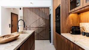 Een moderne keuken met houten kastjes, een marmeren aanrecht en een ingebouwde koffieapparaat.