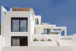 A modern multi-story building with a flat roof, large windows, and a staircase leading to an upper level. - Award Winning Villa w BBQ, Sauna & 250m to Beach (Μυρθιανος Πλακιάς)