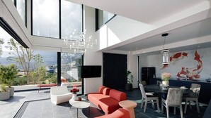 Un salon moderne avec un canapé rouge, une table à manger et des chaises, un lustre et une fresque murale représentant des poissons koï.