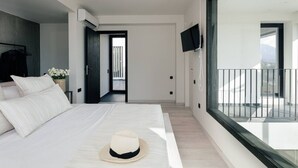 Une chambre moderne dotée d’un grand lit, d’un téléviseur à écran plat et d’un balcon offrant une vue agréable.