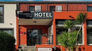 Un hotel moderno con fachada de estilo urbano, entrada a un restaurante y cielo despejado.