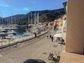 A marina with boats docked, a pedestrian walkway, and buildings along the waterfront.