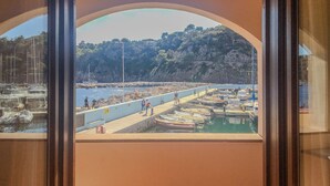 Una marina costera con barcos amarrados, un muelle y acantilados rocosos al fondo.