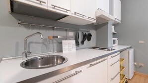 Une cuisine moderne dotée d’appareils électroménagers en acier inoxydable, de meubles blancs et d’un four à micro-ondes encastré.