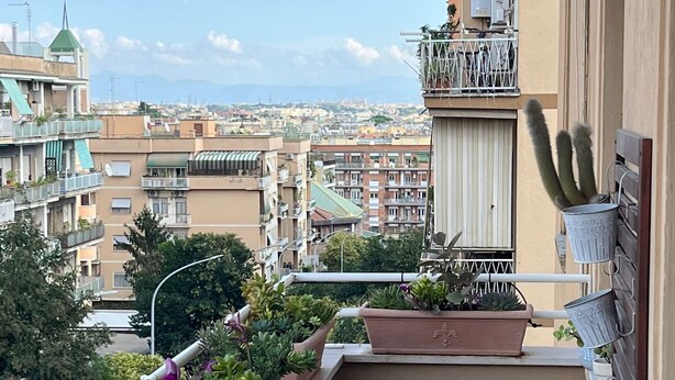 Un balcon agrémenté de plantes en pot, une table en bois et une vue sur le paysage urbain.