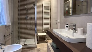 Une salle de bain moderne dotée d’une douche à l’italienne, d’une baignoire sur pieds, d’un grand miroir et d’un meuble-lavabo avec un évier et un plan de travail.