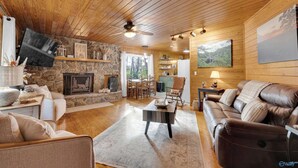 Una sala de estar acogedora con chimenea de piedra, techo de madera y un espacio de descanso confortable.