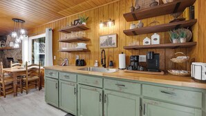 Una cocina con armarios de madera, encimera de madera y diversos electrodomésticos.