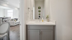 Un baño moderno con un espejo grande, un lavamanos blanco y un mueble gris.