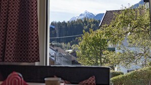 A room with a table and a window offering a view of mountains and a lake. - BERGLIEBE (Kaprun)