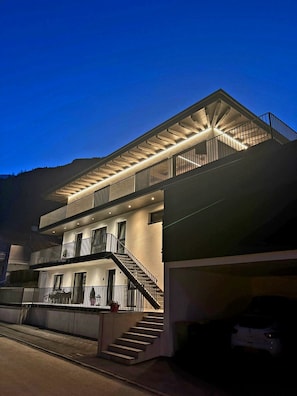 A modern multi-story building with a prominent staircase and a covered balcony area.