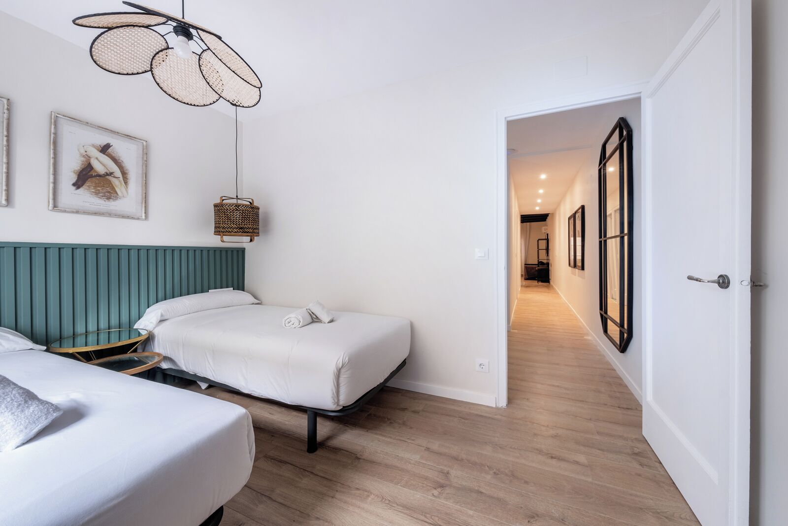 Une chambre d’hôtel avec un lit, une table de chevet, un luminaire suspendu et un tableau encadré au mur.