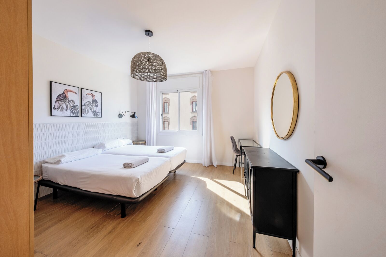Une chambre moderne avec un lit, des tables de chevet, un bureau et une grande fenêtre.