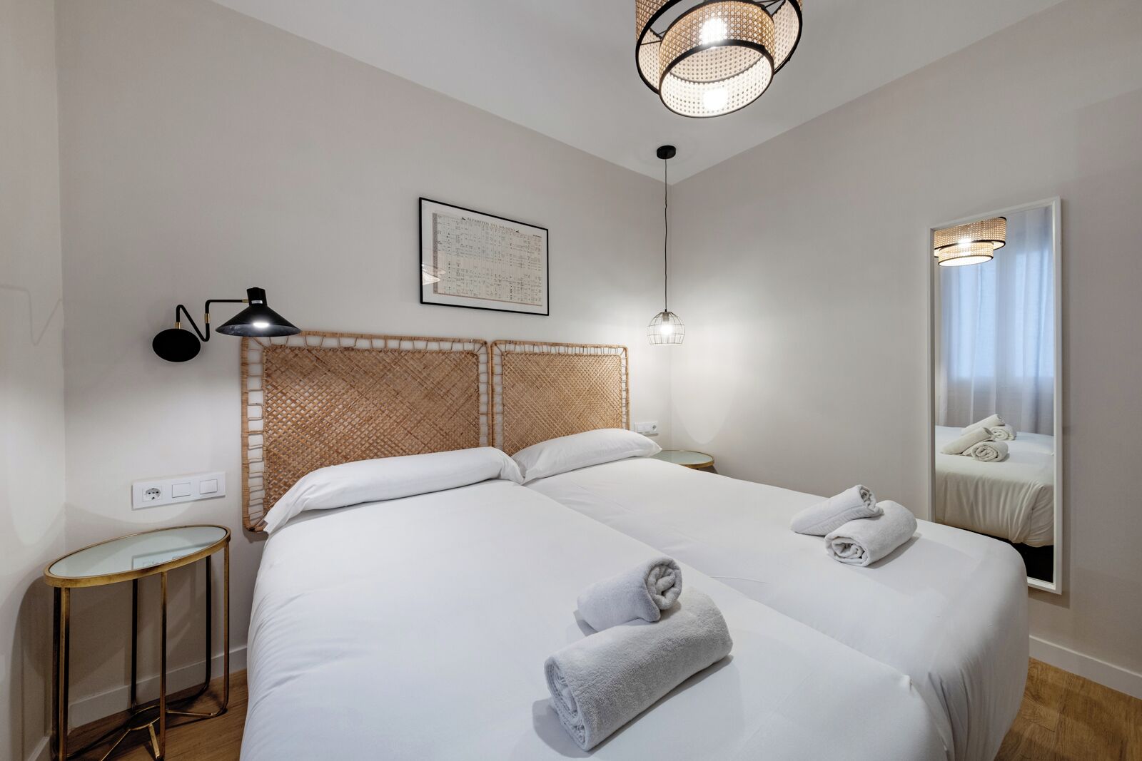 A hotel room with a large bed, a bedside table, a lamp, a mirror, and a framed picture on the wall.
