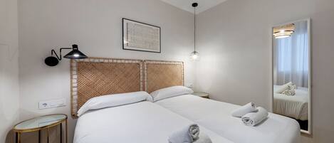 A hotel room with a large bed, a bedside table, a lamp, a mirror, and a framed picture on the wall.