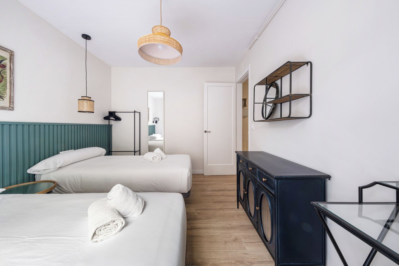 A hotel room with two beds, a washing machine, a mirror, and a small table.