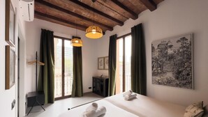 A hotel room with two beds, a large window with curtains, a painting on the wall, and a hanging light fixture. - BeBarceloner Poble Nou Apartments (Barcelona)