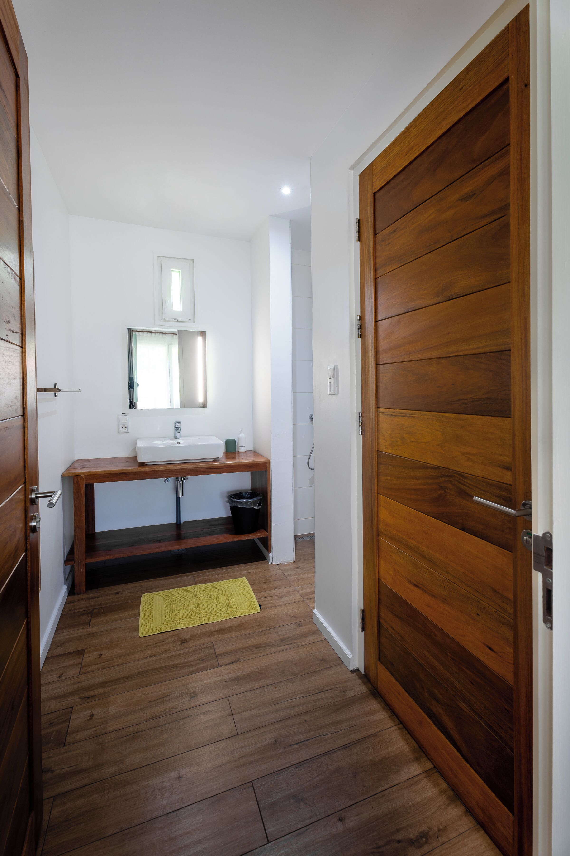 A bathroom with a wooden vanity, a mirror, and a sink.