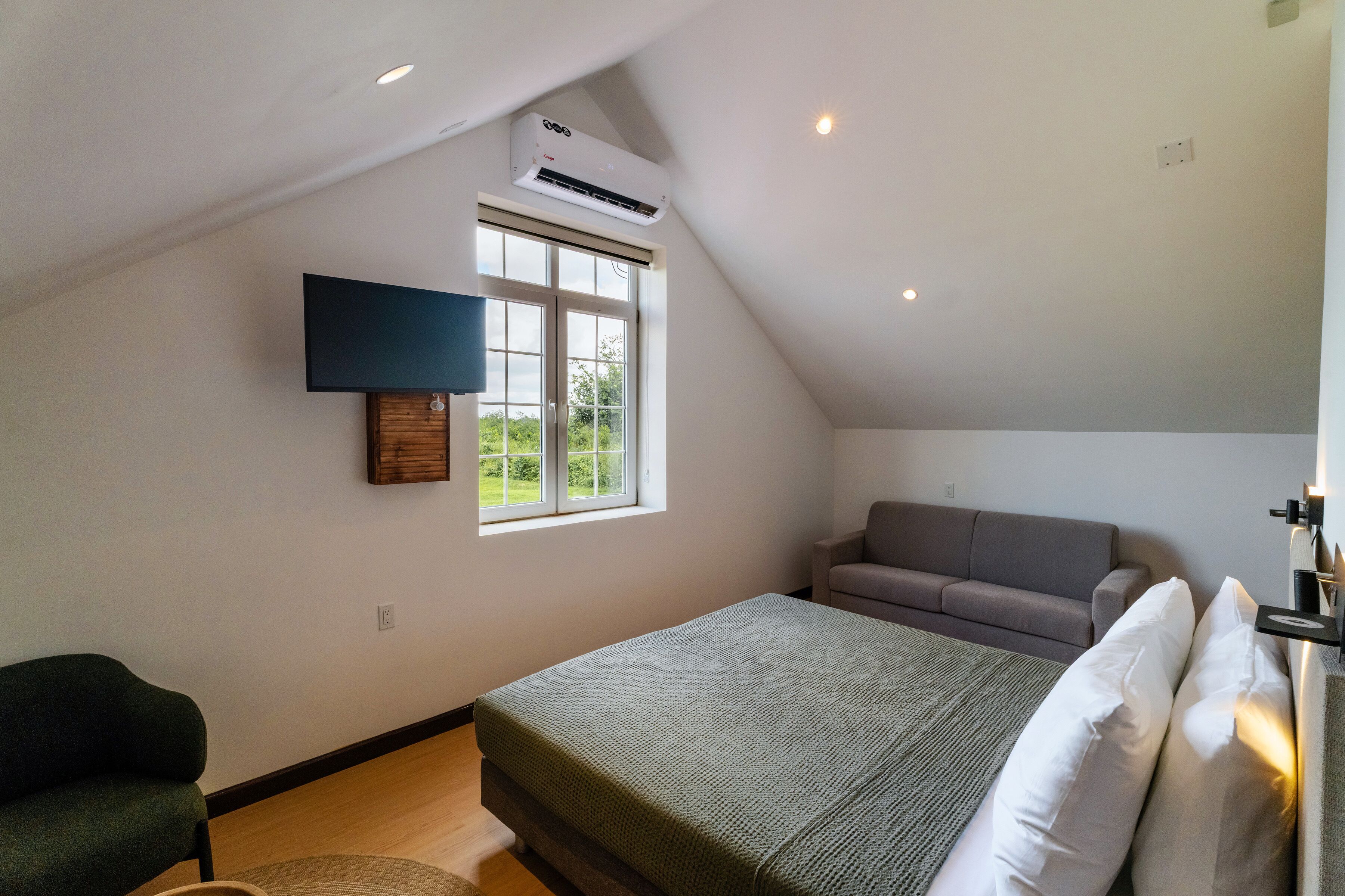 Ein Schlafzimmer mit einem Bett, einem Sofa, einem Fernseher und einem Fenster.