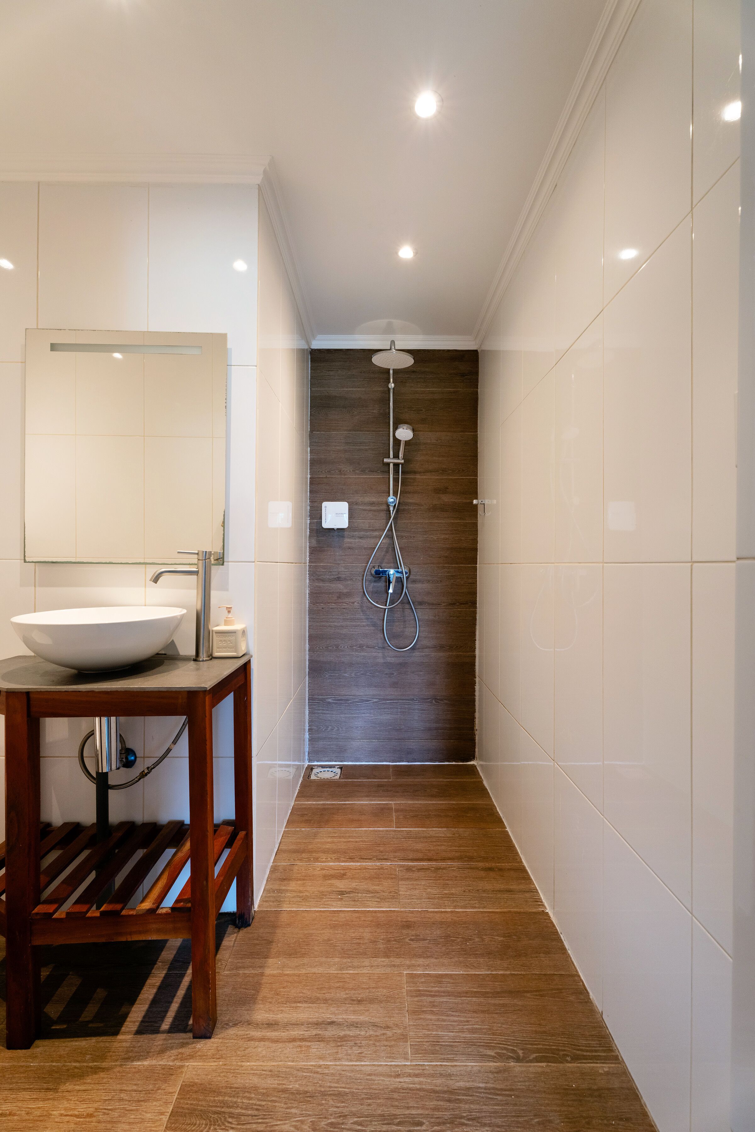 A modern bathroom with a wooden vanity, a large mirror, and a shower area.