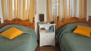 A room with two wooden beds, a nightstand, and curtains.