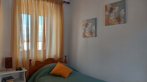 A bedroom with a bed, a nightstand, and two wall-mounted paintings.