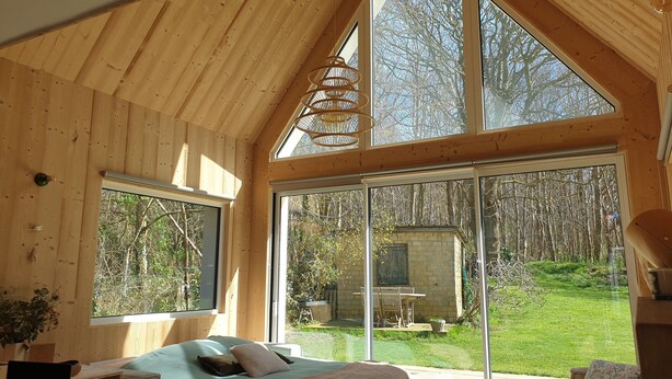 A wooden cabin with a loft bedroom, large windows, and a view of a garden. - Quiet lodge in Wissant, in the forest and 500m from the beach.  Ideal for a couple (Wissant)