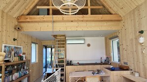A wooden interior with a dining area, kitchen, and bookshelves. - Quiet lodge in Wissant, in the forest and 500m from the beach.  Ideal for a couple (Wissant)