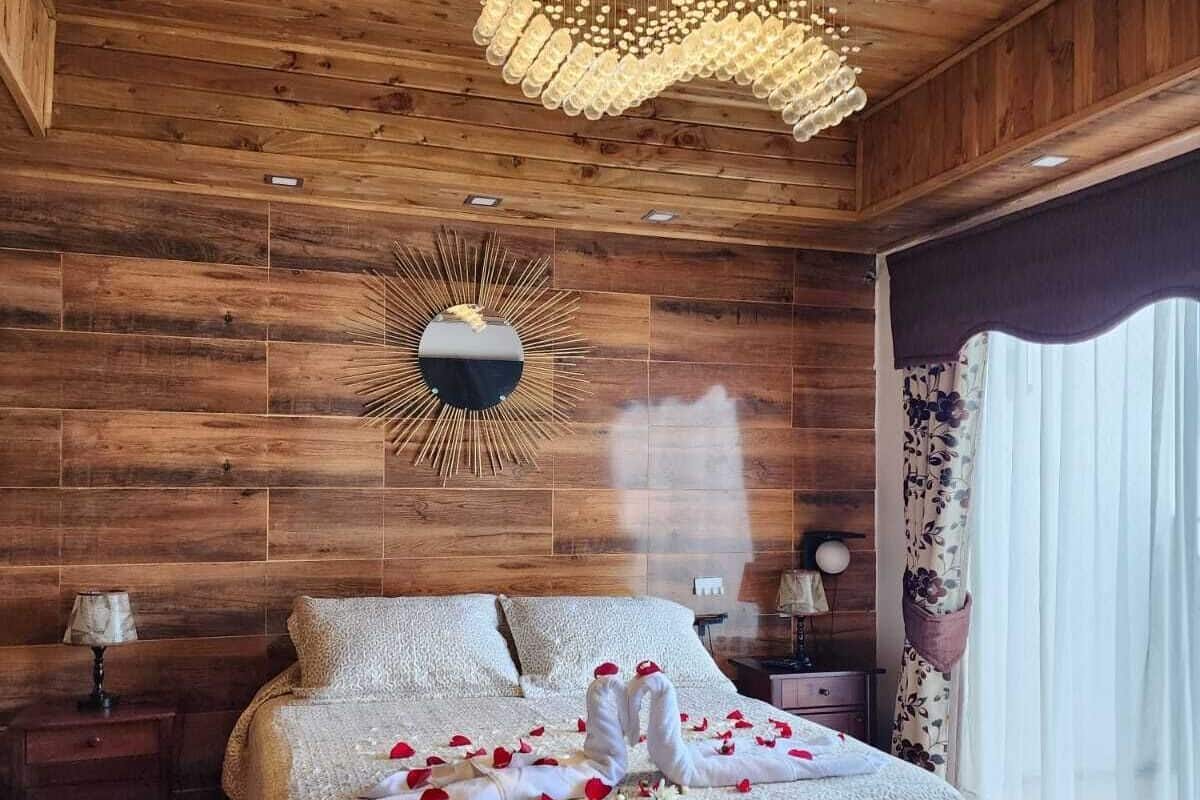A wooden-paneled bedroom with a bed, a chandelier, and a mirror on the wall.