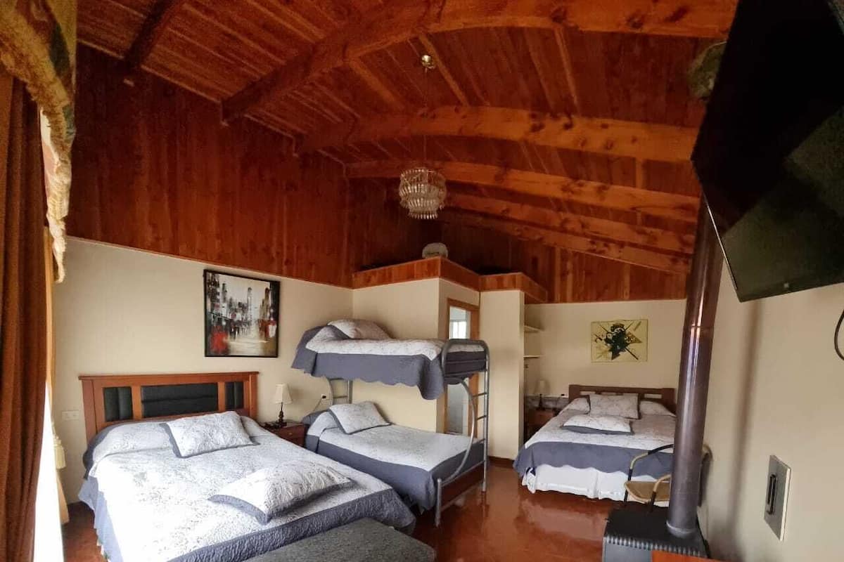 A cozy cabin-style room with three bunk beds, a wooden ceiling, and a fireplace.