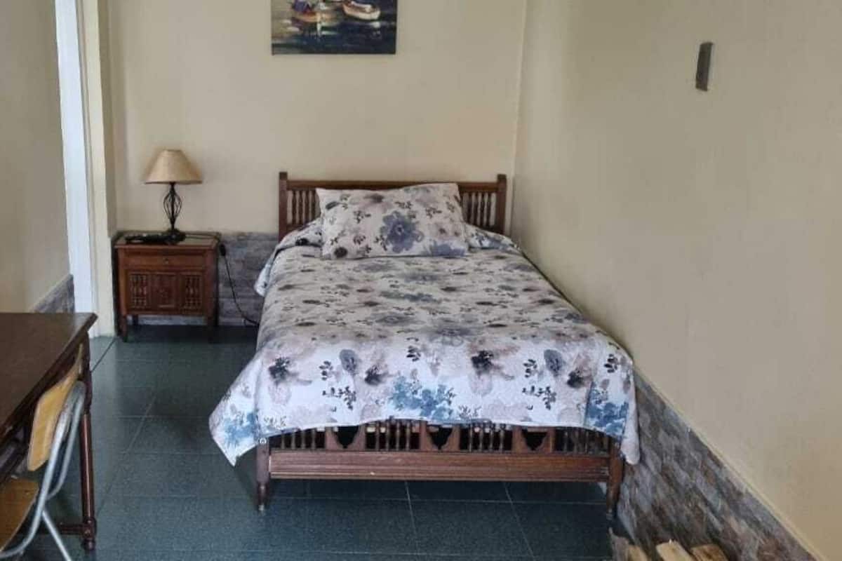 A bedroom with a wooden bed, a nightstand with a lamp, and a wooden wardrobe.