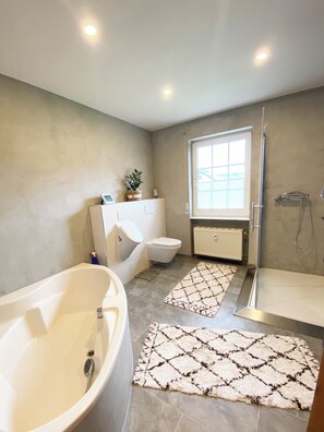 Features a bathtub, walk-in shower, and toilet.