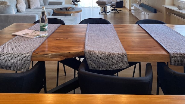 A spacious living area with a wooden ceiling, a large dining table with patterned placemats, and a modern sofa. - Apartment Sonnenlay OG (Brauneberg)