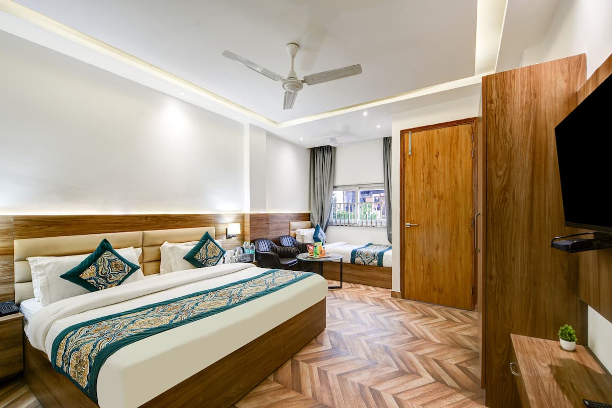 Une chambre d’hôtel avec un grand lit, un bureau, une chaise, une télévision et un ventilateur de plafond.