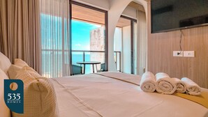Ein Hotelzimmer mit Bett, Fernseher und Meerblick.