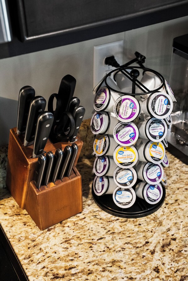 A kitchen counter with a knife block and a container of coffee pods.