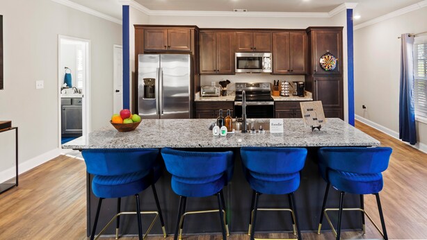 A modern kitchen with a central island, bar stools, and stainless steel appliances. - Modern 4BR Athens Retreat | Massage Chairs | Sleeps 9 | Near UGA & Downtown (Athens)