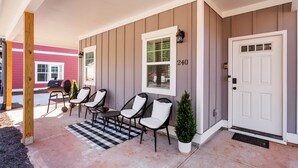 A front porch with a checkered rug, three chairs, a small Christmas tree, and a grill. - Modern 4BR Athens Retreat | Massage Chairs | Sleeps 9 | Near UGA & Downtown (Athens)