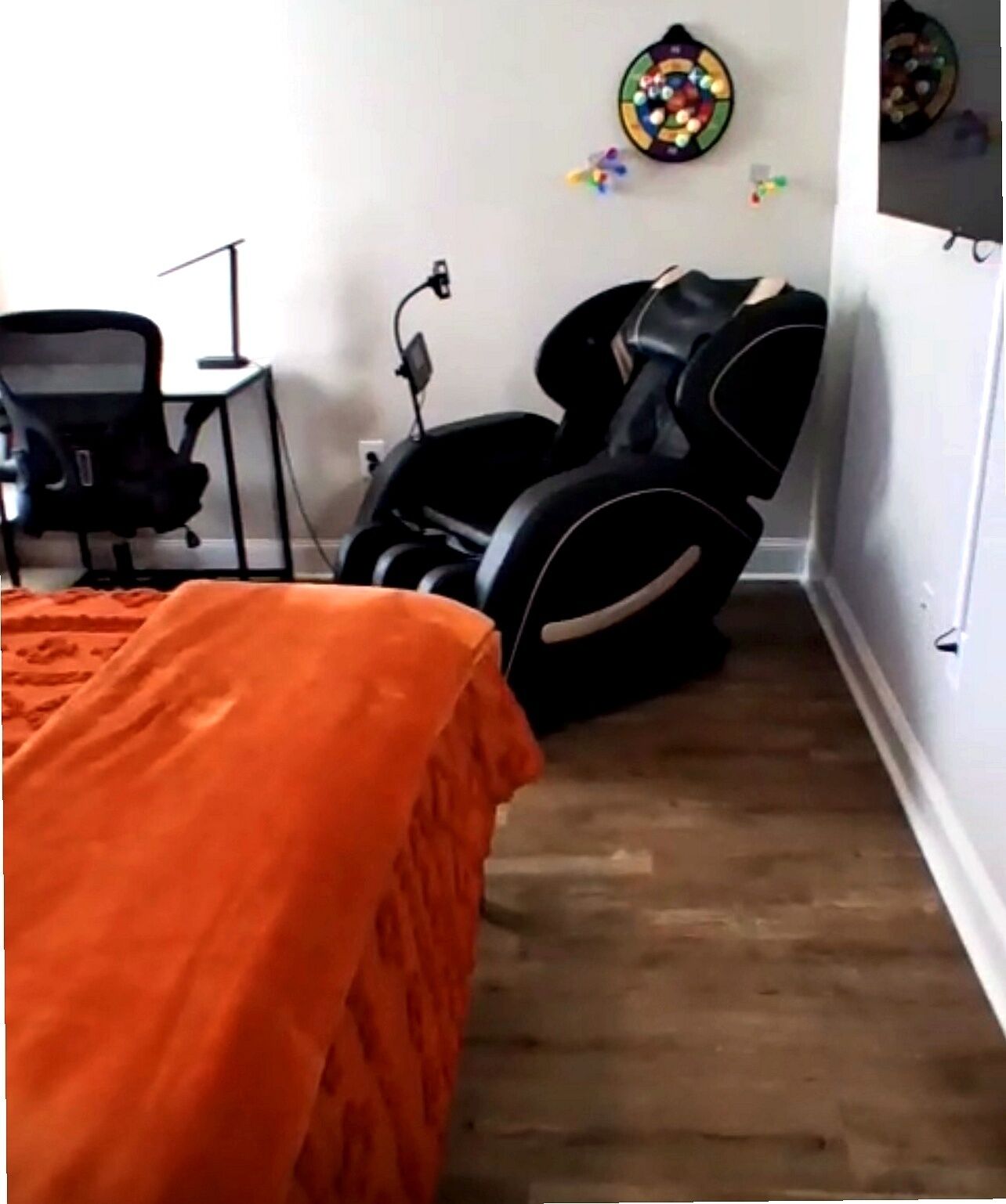 Ein Schlafzimmer mit einem Bett, einem Massagesessel, einem Schreibtisch und einer Wanddekoration.