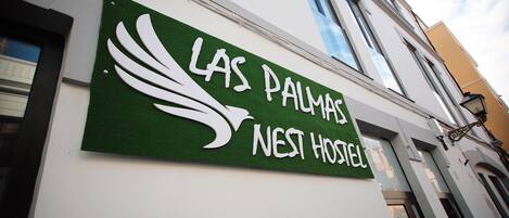 A sign for "Las Palmas Nest Hotel" with a stylized bird logo.