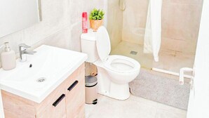 Un baño moderno con lavamanos, inodoro y ducha blancos.