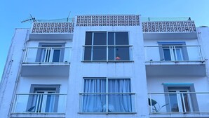 Un edificio de varios pisos con balcones, un letrero que dice "Hostal El Cisne By Nest" y una maceta con planta afuera.