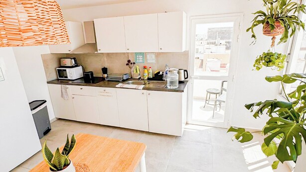 Una cocina moderna con armarios blancos, una mesa de comedor de madera y una planta en maceta.