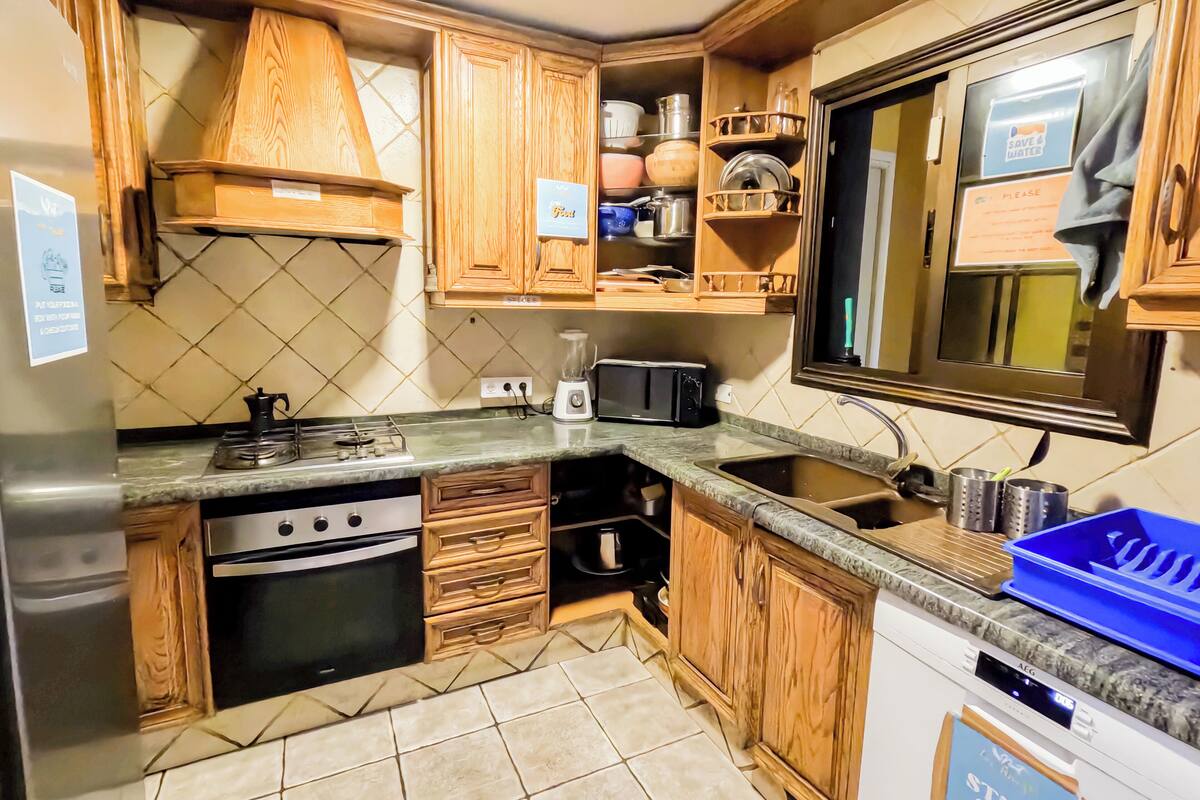 Una cocina compacta con armarios de madera, horno empotrado, microondas y pileta.