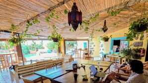 Een restaurant met houten meubels, een tafel met een laptop en hangplanten.