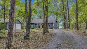 A rustic cabin with a gravel driveway, surrounded by tall trees and a clear sky. - Bear Brow Cabin. Amazing view from brow to valley below. (Mentone)