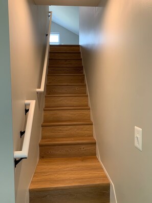 A wooden staircase with white handrails, leading to a room with a window.