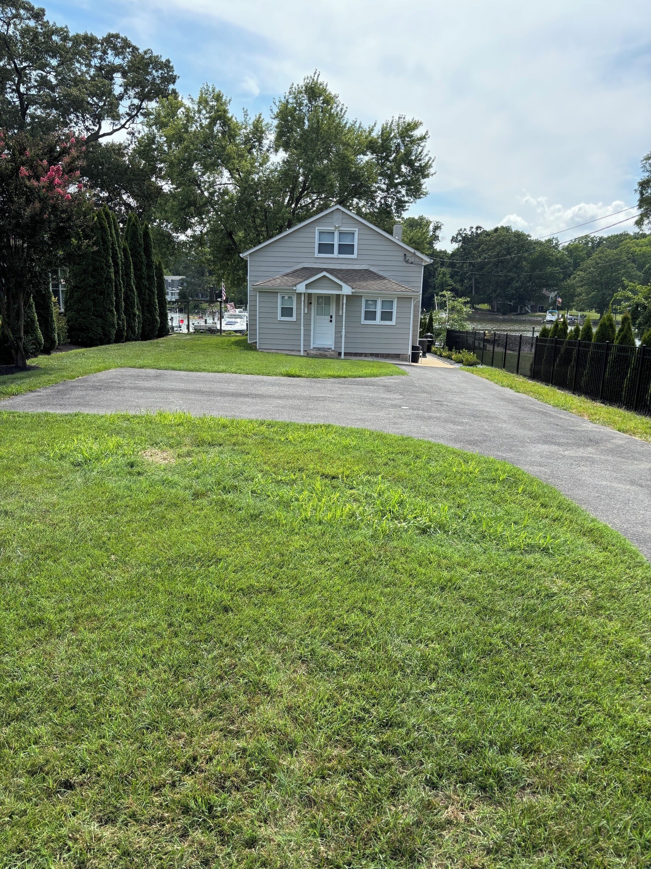 A two-story house with a front porch, a driveway, and a well-maintained lawn.